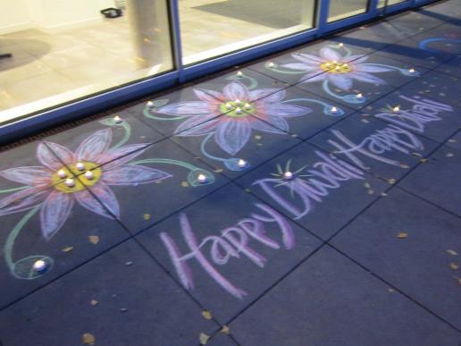 A chalk lotus flower rangoli motive by cosma terra ccc and done with a visitor who spontaneously wanted to draw, too, at the Diwali Festival.  Kreide Lotus Rangoli, cosma terra ccc mit eine Besucherin die auch spontan mitmachen wollte, Diwali Festival Nürnberg, 27.10.19.